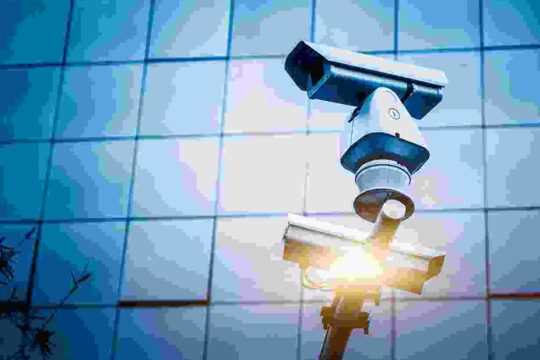 A couple of cameras hanging from the side of a building.