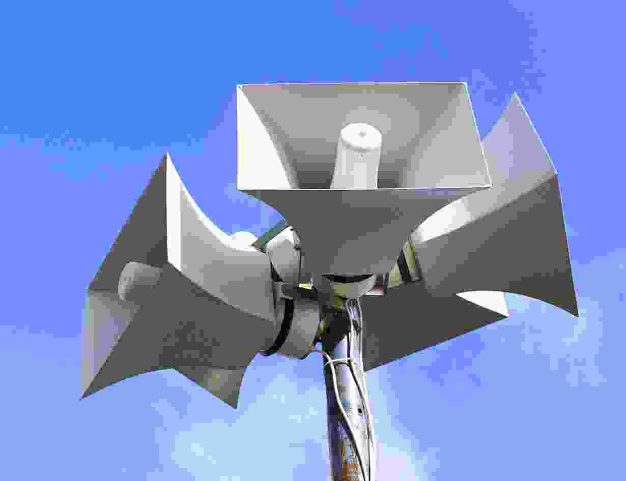 A close up of three speakers on top of a pole