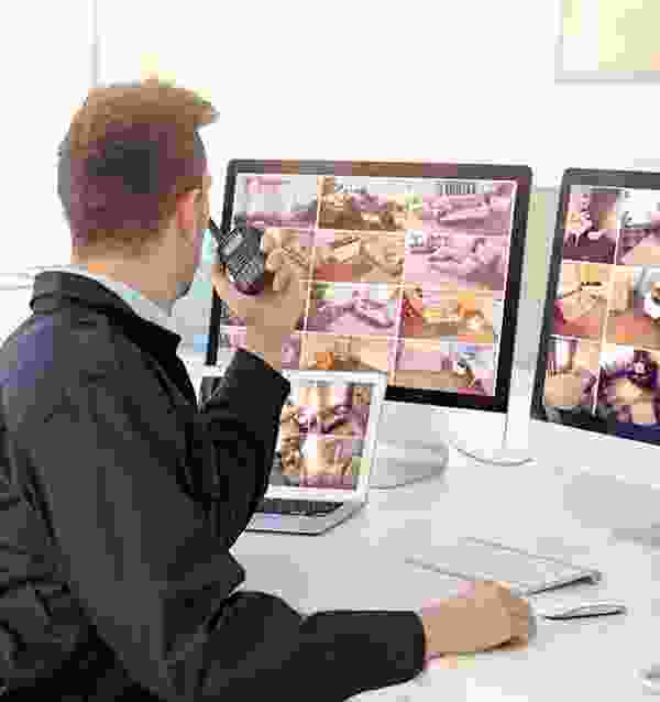 A man sitting at his desk taking pictures of multiple computers.
