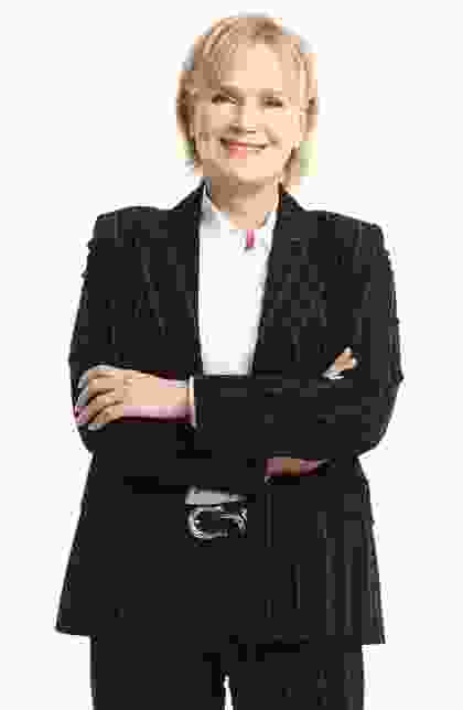 A woman in black jacket standing with her arms crossed.