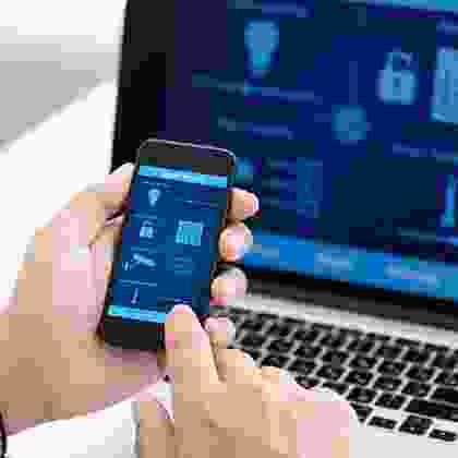 A person holding an iphone in front of a laptop.