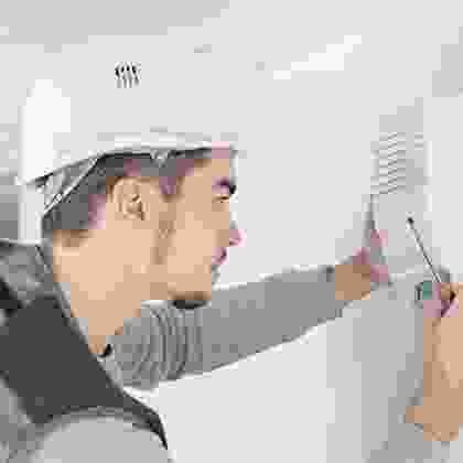 A man in a hard hat is holding a pair of scissors.