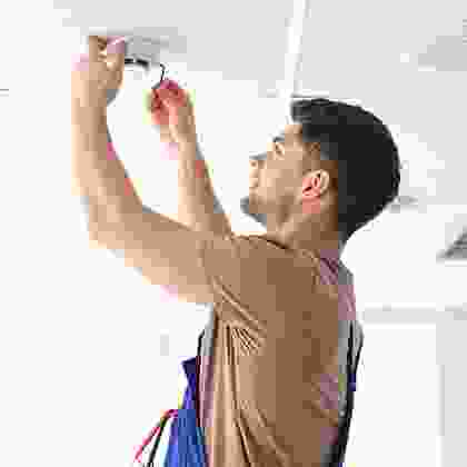 A man holding scissors and painting the wall.