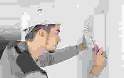 A man in white hard hat and safety vest holding a screwdriver.