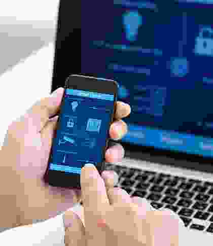 A person holding an iphone in front of a laptop.