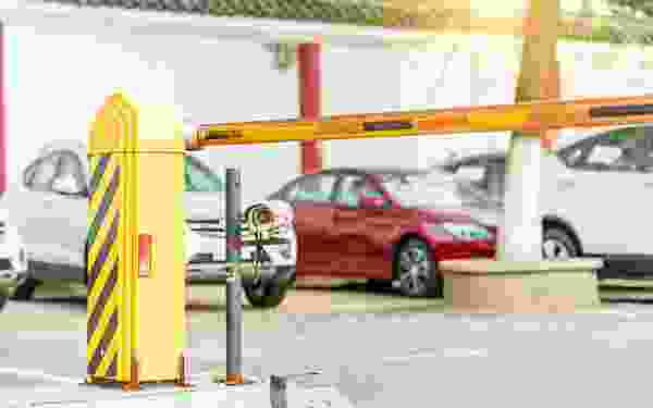 A red car is parked in front of a yellow gate.