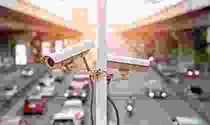 Two cameras on a pole in the middle of a street.