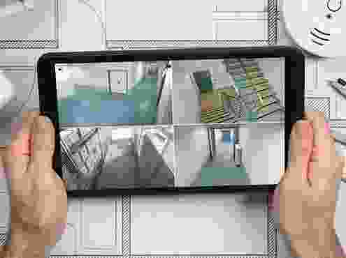 A person holding up a tablet with four images on it.