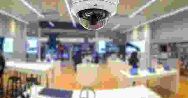 A camera is hanging from the ceiling of an office.