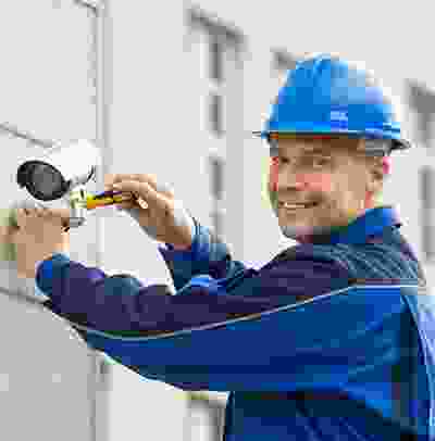 A man in blue and white shirt holding a camera.