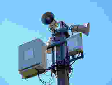 A camera on top of a pole with wires attached to it.