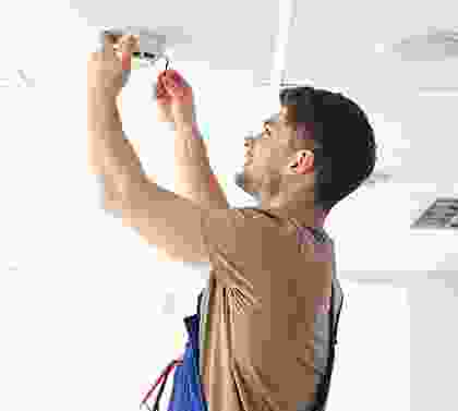 A man holding onto the handle of a light fixture.