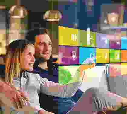 A couple is sitting on the couch watching television.