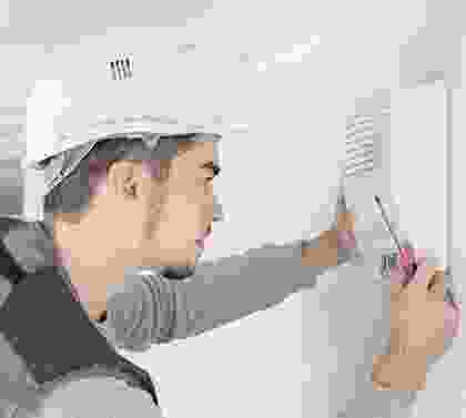 A man in white hard hat holding a pair of scissors.