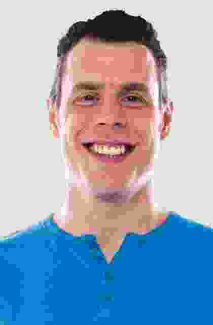 A man in blue shirt smiling for the camera.