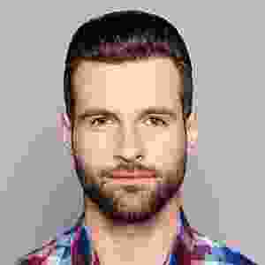 A man with a beard and mustache wearing a plaid shirt.