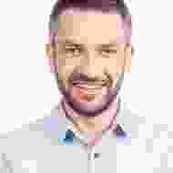 A man with a beard and mustache smiling for the camera.