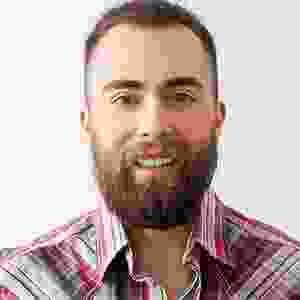 A man with beard and plaid shirt smiling for the camera.