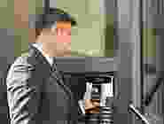 A man in a suit and tie standing next to an atm machine.