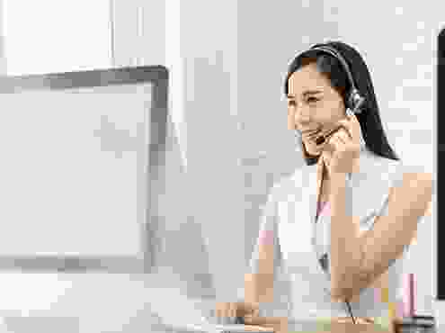 A woman with headphones on sitting at a desk.