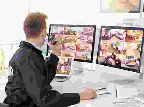 A man sitting at a desk with two computers.